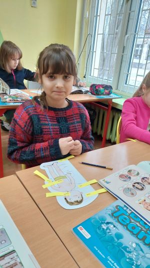 Dzieci siedzące w ławkach wykonując