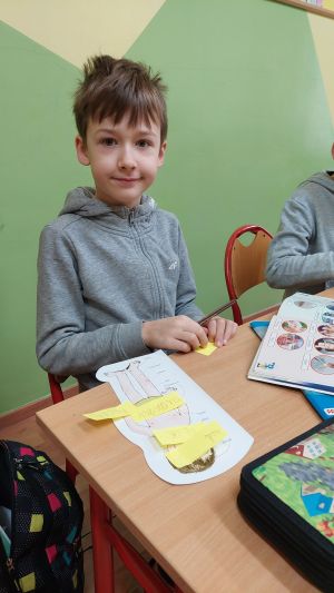 Dzieci siedzące w ławkach wykonując