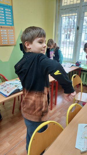 Dziecko siedzące w ławkach wykonujące zadanie