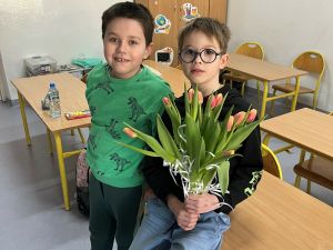 Chłopcy wręczający tulipany dziewczynkom.