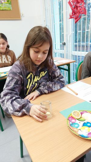 Uczniowie siędzą w ławkach i wykonują eksperymenty