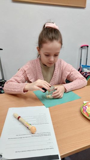 Uczniowie siędzą w ławkach i wykonują eksperymenty