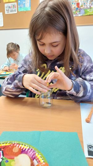 Uczniowie siędzą w ławkach i wykonują eksperymenty