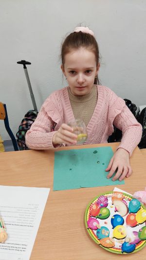 Uczniowie siędzą w ławkach i wykonują eksperymenty