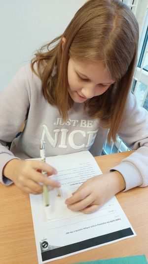 Uczniowie siędzą w ławkach i wykonują eksperymenty