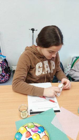 Uczniowie siędzą w ławkach i wykonują eksperymenty
