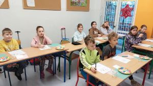Uczniowie siędzą w ławkach i wykonują eksperymenty