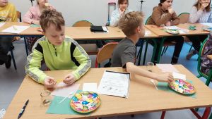 Uczniowie siędzą w ławkach i wykonują eksperymenty