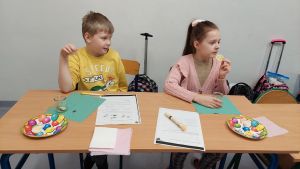 Uczniowie siędzą w ławkach i wykonują eksperymenty