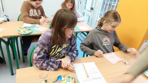 Uczniowie siędzą w ławkach i wykonują eksperymenty