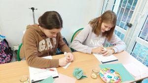 Uczniowie siędzą w ławkach i wykonują eksperymenty