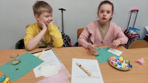 Uczniowie siędzą w ławkach i wykonują eksperymenty