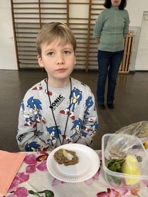 Uczniowie siedzący przy stole przygotowują kanapki