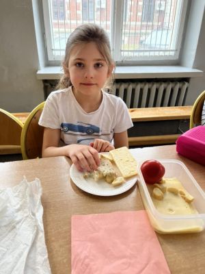 Uczniowie siedzący przy stole przygotowują kanapki