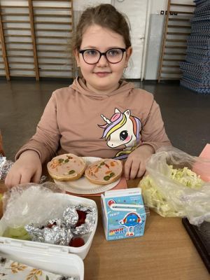 Uczniowie siedzący przy stole przygotowują kanapki