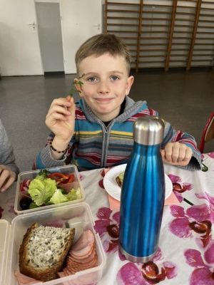 Uczniowie siedzący przy stole przygotowują kanapki