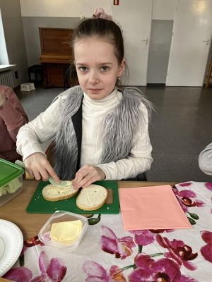 Uczniowie siedzący przy stole przygotowują kanapki