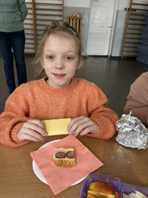 Uczniowie siedzący przy stole przygotowują kanapki