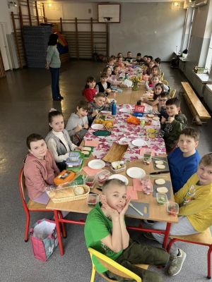Uczniowie siedzący przy stole przygotowują kanapki